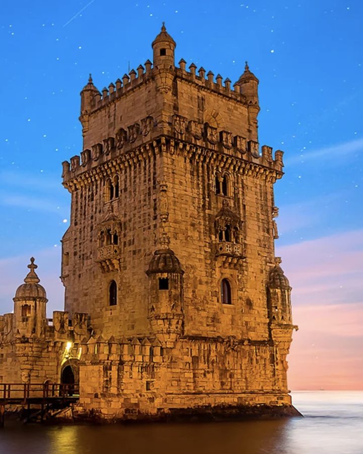Lisbon's Belém Tower glows at dusk beside the Tagus River.