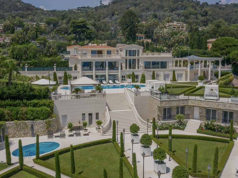 Aerial view of a large white villa with terraced gardens, formal lawns and a swimming pool